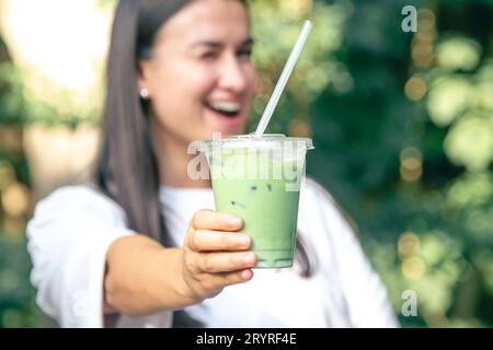 Gefrorener Matcha Latte in einem Plastikbecher in den Händen einer Frau. Stockfoto