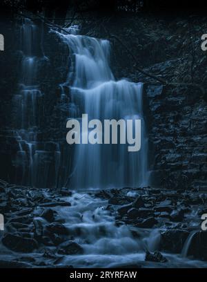 Ein malerischer Blick auf einen Wasserfall, der die Felsen hinunterragt Stockfoto
