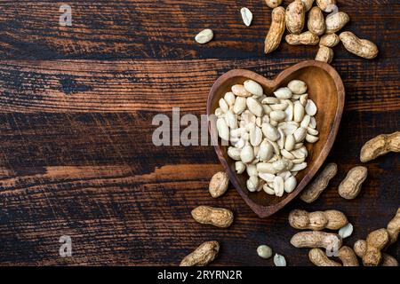 Erdnusssnack in Schüssel auf dunklem Hintergrund Stockfoto