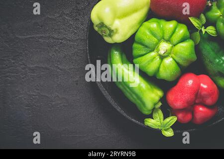 Gusseiserne Schale mit verschiedenen roten und grünen Paprika mit Wassertropfen Stockfoto