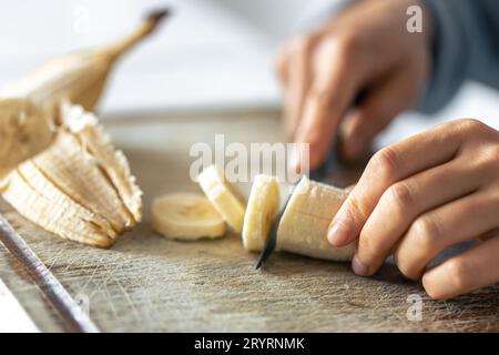 Eine Frau schneidet eine Banane auf einem Schneidebrett. Stockfoto