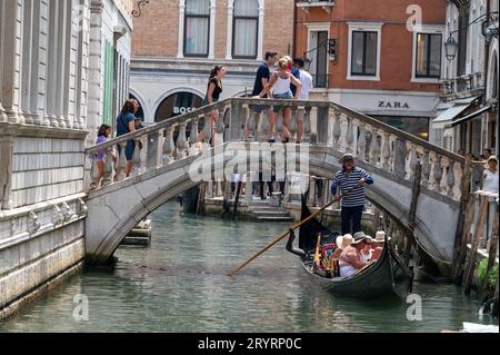 Ein Gondolier lenkt seine Gondel unter einer der vielen niedrigen Fußgängerbrücken in den Canale Grande in der Nähe der Rialto-Brücke in Venedig in der Region Veneto Stockfoto