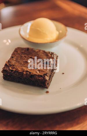 Ein vertikaler Schuss eines appetitlichen Brownie mit einer Schaufel Eis auf einem runden Teller Stockfoto