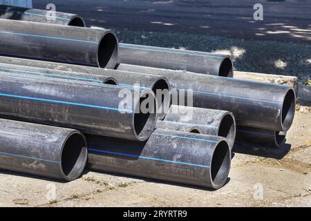 Schwarze Kunststoffleitungen. Ein Haufen von Polyethylenrohren für eine Wasserversorgung. Objekte für die Verlegung von Stadtkommunikation und Kanalisation. Die Konz Stockfoto