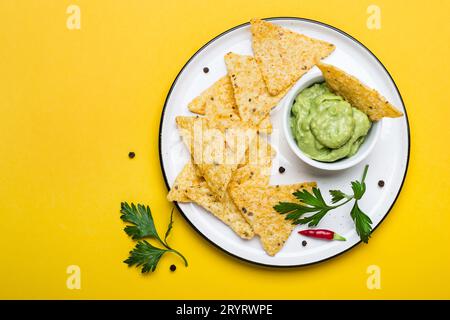 Traditionelle lateinamerikanische Guacamole mit Corn Chips Nachos auf gelbem Hintergrund Stockfoto