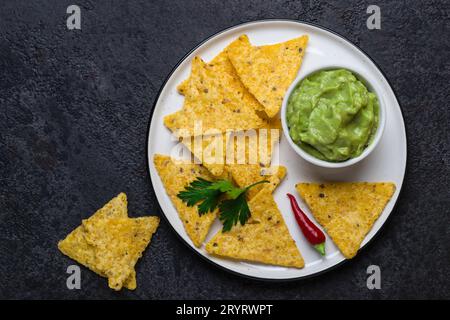 Traditionelle lateinamerikanische Guacamole mit Corn Chips Nachos auf schwarzem Hintergrund Stockfoto