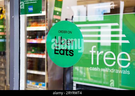 Bestellen Sie auf Uber Eats runder grüner Aufkleber in McColl's Shops im Stadtzentrum von Exeter Stockfoto