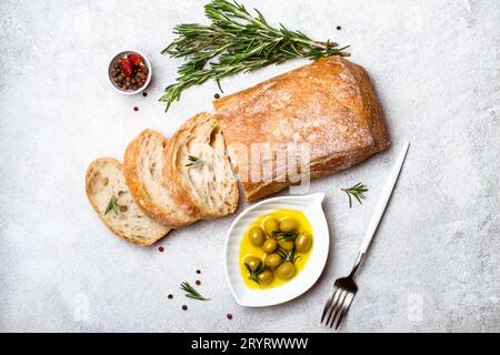 Italienisches Ciabatta-Brot, in Scheiben geschnitten mit Kräutern und Oliven Stockfoto