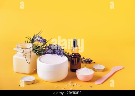 Lavendelöl, Creme, Peeling, Maske und Salz auf gelbem Hintergrund. Natürliche heimwerkerkosmetik-Produkte, Körperpflege zu Hause Stockfoto