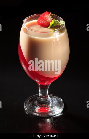 Kirsch und Milchgelee im Glas mit Minzblättern und einer Erdbeere Stockfoto