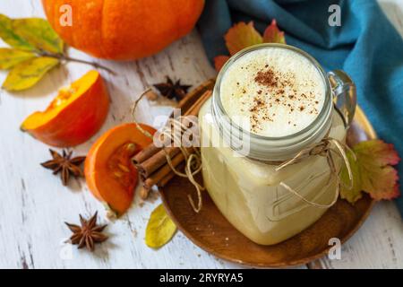 Herbstgetränk. Kürbis gewürzter Latte oder Kaffee im Glas auf einem rustikalen Holztisch. Stockfoto