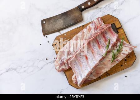 Rohes Kalbsbriketts Fleisch mit Rosmarin und Gewürzen auf kurzen Rippen zum Kochen auf Marmorplatte. Draufsicht, flach liegend. Stockfoto