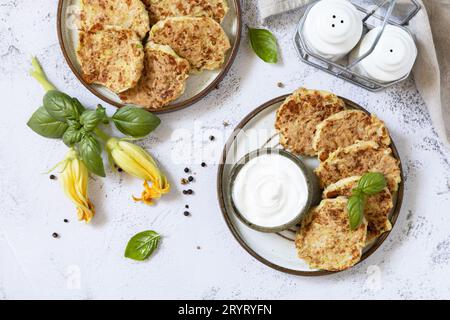 Zucchini-Krapfen. Vegetarische Zucchini-Pfannkuchen mit Käse, serviert mit Sauerrahm auf einem rustikalen Holztisch. Gesundes Essen, niedrig Stockfoto