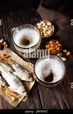 Alkohol trinken ein Pint von Lager und ein Pint von Stout, Craft Beer. Zwei Gläser Bier mit Schaum und Snacks auf rustikalem Holzhintergrund. Stockfoto
