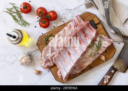 Rohes Kalbsbriketts Fleisch mit Gemüse und Gewürzen auf kurzen Rippen zum Kochen auf Marmorplatte. Draufsicht, flach liegend. Stockfoto