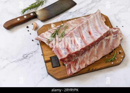 Rohes Kalbsbriketts Fleisch mit Rosmarin und Gewürzen auf kurzen Rippen zum Kochen auf Marmorplatte. Stockfoto