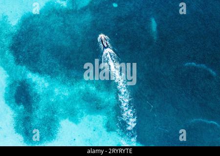 Eine Luftaufnahme eines Bootes, das an der Küste vorbei segelt, umgeben von blauem Wasser in Roatan Honduras Stockfoto