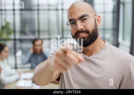 Lässiger Bärtiger Geschäftsmann, Der Lächelnd Auf Ihr Büro Zeigt Stockfoto