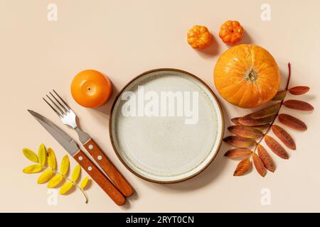 Herbsttisch für Halloween oder Thanksgiving. Herbsthintergrund mit einem leeren Teller, Besteck, Kürbissen. Thanksgiving Backg Stockfoto