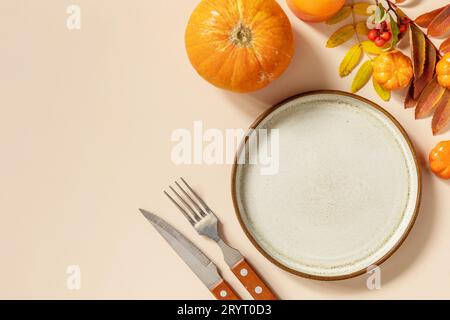 Herbsttisch für Halloween oder Thanksgiving. Herbsthintergrund mit einem leeren Teller, Besteck, Kürbissen. Thanksgiving Backg Stockfoto