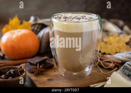 Saisonales Herbstkonzept mit Heißgetränk. Kürbis Latte Gewürzkaffee, warmer Schal und Ahornblätter auf rustikalem Hintergrund. Stockfoto