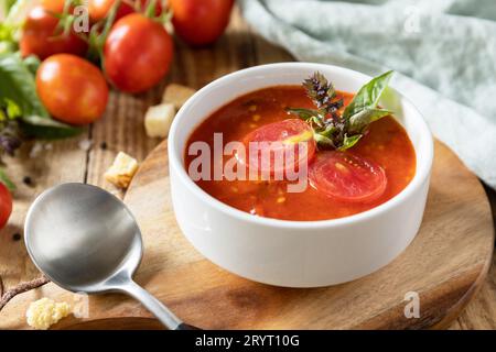Schale Tomatencremesuppe mit Basilikum und Croutons auf einem rustikalen Tisch. Vegane Suppenpüree Tomaten. Gesunde Ernährung mit niedrigem Kohlenhydratgehalt. Stockfoto