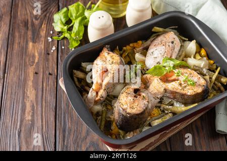 Gesunde gebackene Fisch Lachssteaks mit Basilikum, grünen Bohnen und süßen Paprika auf einem rustikalen Tisch. Low Carb Dinner, gesunde Ernährung Stockfoto