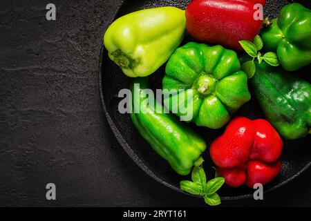 Verschiedene rote und grüne Paprika mit Wassertropfen auf gusseiserner Schale Stockfoto