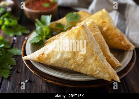 Asiatisches Essen. Vegetarische samsa (Samosas) mit Tomatensoße auf einem Holztisch. Beliebt in Indonesien als Risoles Sayur. Stockfoto