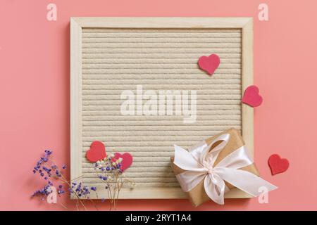 Geschenkbox mit Bögen, kleinen Herzen und gypsophila-Blumen auf pastellrosa Hintergrund mit leerem Raum. Muttertag, Hochzeit, Valenz Stockfoto