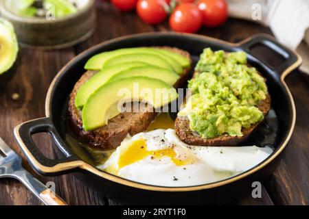 Gesundes Frühstück, Sandwich mit Avocado und Ei, Vollkornbrot, Avocado in Scheiben und pochiertes Ei auf einem rustikalen Tisch. Stockfoto