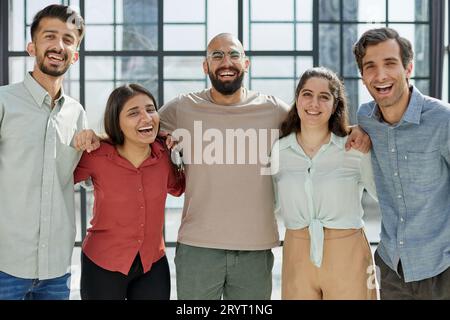 Porträt von glücklichen, begeisterten Geschäftspartnern Kollegen unterschiedlicher Art, die in die Kamera schauen und umarmen Stockfoto