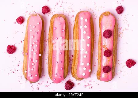 Kreatives Layout aus Eclairs mit rosa Glasur auf weißem Hintergrund. Lebensmittelkonzept Stockfoto