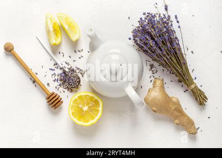 Lavendelkräutertee in einer weißen Teekanne, Zitrone und Ingwer Stockfoto