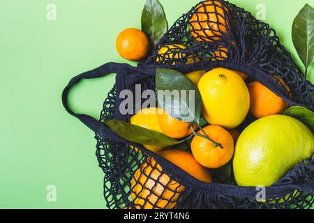 Schwarze Textiltasche voller farbenfroher Zitrusfrüchte. Gesunde Lebensmittel und Null-Abfall-Konzept Stockfoto