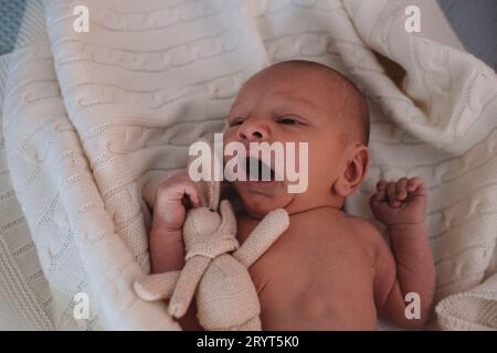 Das kleine süße neugeborene Baby liegt in eine weiße Decke auf dem Bett Stockfoto