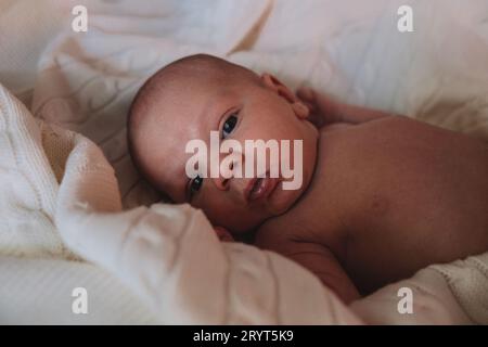 Das kleine süße neugeborene Baby liegt in eine weiße Decke auf dem Bett Stockfoto