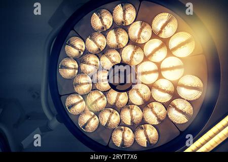 Ansicht eines großen eingeschalteten Lichts von unten nach oben, das über einem Operationstisch in einem Krankenhaus hängt. Stockfoto