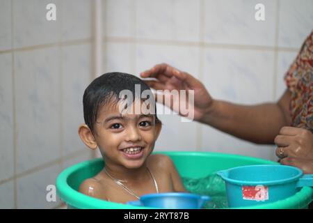 Ein 2-jähriger indischer Junge, der in einer grünen Badewanne badet. Stockfoto