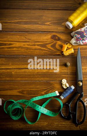 Ein Satz Werkzeuge und Fäden zum Nähen von Kleidung auf Holzhintergrund. Stockfoto