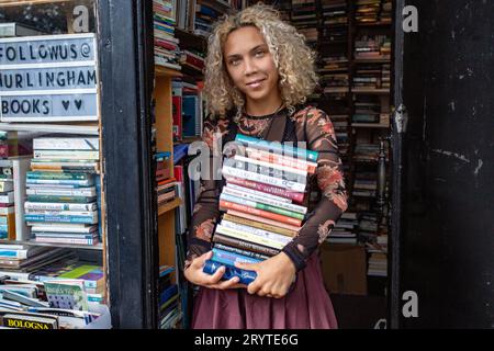 GREAT BRITAN / London / Hurlingham Books / Attraktive Frau mit einem Stapel Bücher. Stockfoto