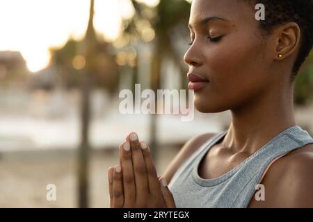 Entspannte afroamerikanische Frau, die Yoga-Meditation am sonnigen Strand praktiziert, Kopierraum Stockfoto