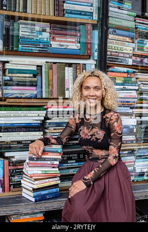 GREAT BRITAN / London / Hurlingham Books / Attraktive Frau mit einem Stapel Bücher. Stockfoto