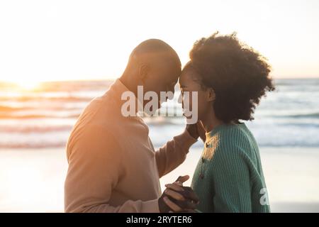 Glückliches afroamerikanisches Paar, das am sonnigen Strand tanzt und lächelt Stockfoto