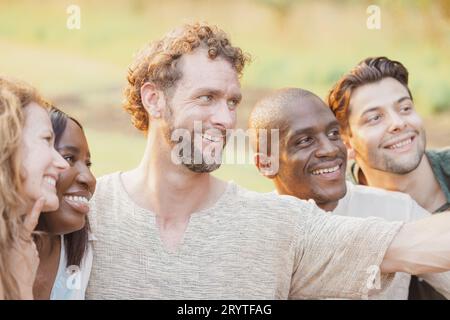 Multirassische Gruppe junger glücklicher Menschen, die lächeln und Selfie machen, während sie im Sommer draußen spazieren gehen Stockfoto