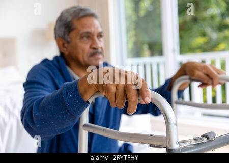 Birassischer Seniorenmann, der zu Hause mit Krücken auf dem Bett sitzt Stockfoto