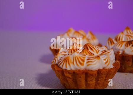 Ein frisch gebackener Cupcake mit Creme auf einer weißen Tafel vor einem lila Hintergrund Stockfoto