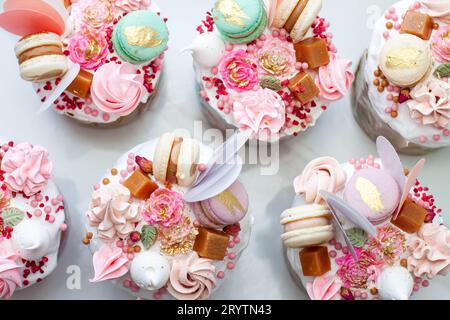 Festliche Collage mit orthodoxem osterbrot, reich dekoriert mit Süßigkeiten, Makronen, Schokolade und essbaren Blumen Stockfoto