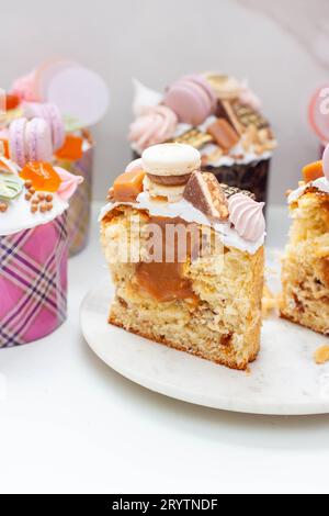 Orthodoxes osterbrot reich dekoriert mit Süßigkeiten, Makronen, Schokolade und essbaren Blüten mit gesalzener Karamellfüllung Stockfoto