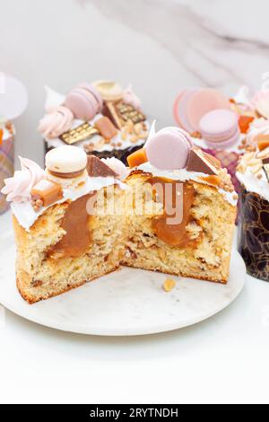 Orthodoxes osterbrot reich dekoriert mit Süßigkeiten, Makronen, Schokolade und essbaren Blüten mit gesalzener Karamellfüllung Stockfoto